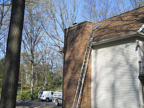 Brick chimney on a White House with Clean Sweep vans in the background